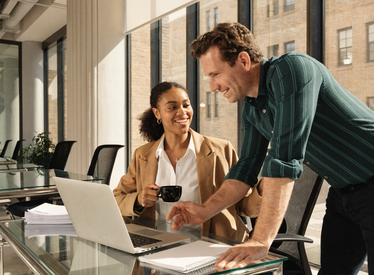 Two colleagues collaborating over a laptop in a modern office